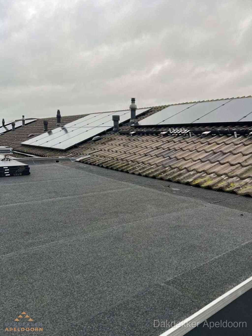 Plat dak inspectie met bitumen bedekking naast schuin pannendak in Apeldoorn